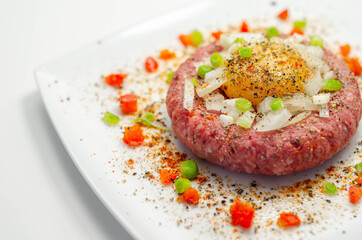 Beef steak tartare with raw egg yolk and onion with tomato