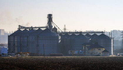 Fototapeta na wymiar A plowed field in front of the elevator for grain storage. Grain warehouse.