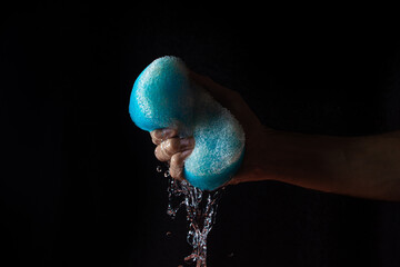 Water on a black background. Water is squeezed out of the bath sponge. Pure water