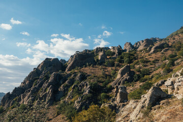 Ridge of brown rocks covered with greenery against a blue sky