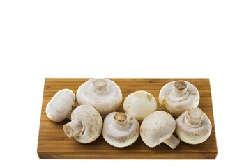 Close up view of white champignon mushrooms on wooden cutting board.