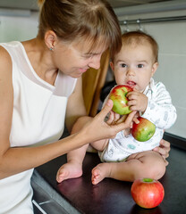 Fototapeta premium Mom and baby in the kitchen eating apples 