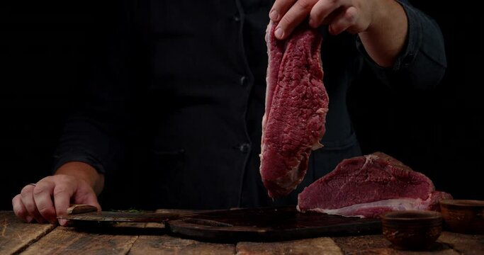 Men's hands hold a piece of raw beef. 