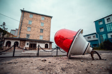 A close-up of a red lamp against the background of buildings. Repair work on the road.