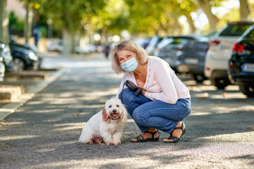 Mature woman walking with a dog outdoors an antivirus mask