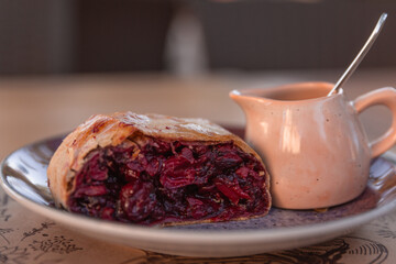 Sliced homemade strudel with cherry close-up on a plate. horizontal