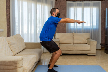 Fototapeta na wymiar Low-bearded man exercising with black and blue sportswear and mask to prevent coronavirus
