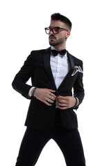 cool young businessman adjusting tuxedo and looking to side