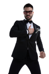 dramatic unshaved man in tuxedo holding hands on chest