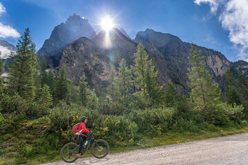 Fototapeta premium pretty senior woman riding her electric mountainbike in the Innerfeld Valley in the Sexten Dolomites near village of Innichen , Tre cime National park, South Tirol, Italy 