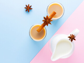 Masala tea and spices on a pink blue background. Masala chai in turkish tea cups. Indian national drink and milk jug on a pastel background. Copy space. Top view