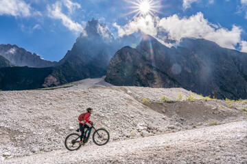 Fototapeta premium pretty senior woman riding her electric mountainbike in the Innerfeld Valley in the Sexten Dolomites near village of Innichen , Tre cime National park, South Tirol, Italy 