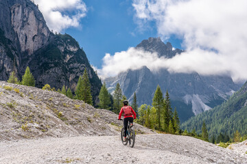 Fototapeta premium pretty senior woman riding her electric mountainbike in the Innerfeld Valley in the Sexten Dolomites near village of Innichen , Tre cime National park, South Tirol, Italy 