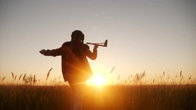 girl kid run in the park across the field play with an toy airplane in his hand a silhouette at sunset lifestyle wants to astronaut pilot. fantasy dream kid concept. child run wheat fun play with toy