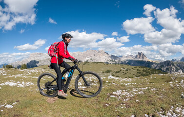 Obraz premium nice senior woman, riding her electric mountain bike below the famous Three peak of Lavaredo in the Sexten Dolomites in South tyrol, Italy