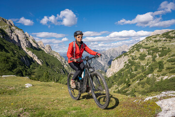 nice and active senior woman riding her electric mountain bike on the high plateau of Pratto Piazzo...