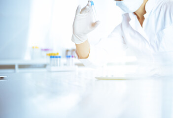 Female laboratory assistant analyzing a blood sample at hospital. Medicine, health care and researching concept