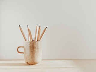 Pencils in a ceramic mug on a table with copy space.
