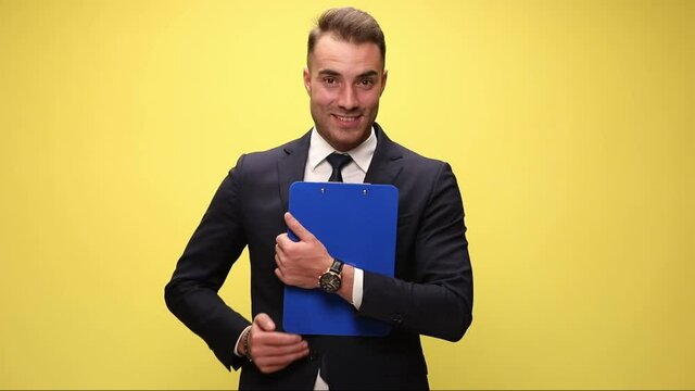 sexy businessman holding his clipboard then giving a thumbs up on yellow background