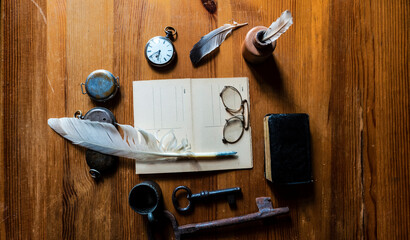wooden desk with ink pen, antique pocket watch, vintage glasses and old textured blank writing...