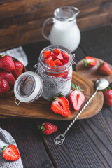 chia pudding with strawberry sauce, fresh berries and milk on rusic background