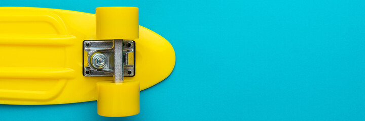 Minimalist flat lay photo of yellow plastic mini cruiser board on blue background. Top view of...