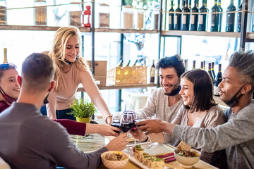 group of friends toasting with wine during dinner in a restaurant, multiethnic group have a fusion dinner with italian and japanese food, new normal concept of social hangout with protective mask