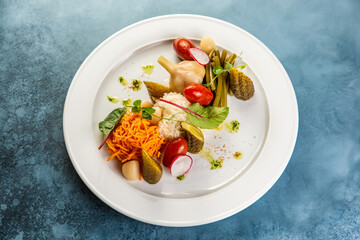 Slices various pickled vegetables on white plate in restaurant