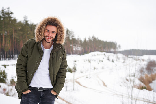 Attractive bearded man standing outdoors in winter season forest.