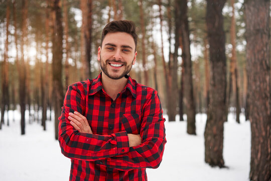 Attractive bearded man standing outdoors in winter season forest.