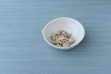 White clay powder lie in white bowl isolated on blue background. Ural food clay. top view. no...