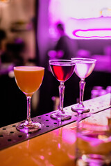 A lifestyle atmospheric photo of a cocktail in a nick and nora glass at the bar in the evening, high iso, selective focus