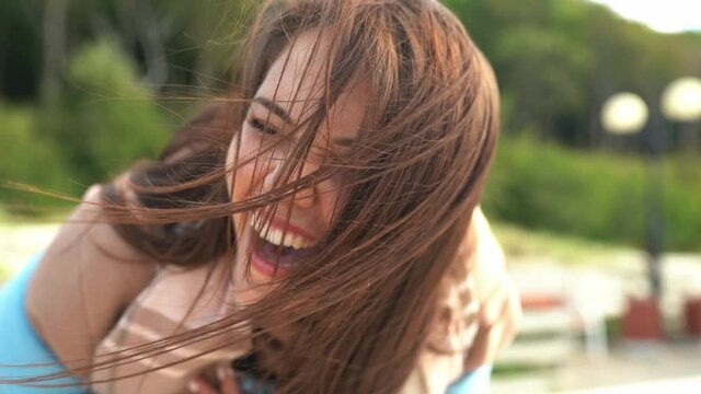 Close up footage of happy laughing young female with long hair swinging on wind. Autumn, seaside, outdoor, vacation, travel