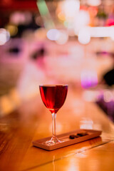 A lifestyle atmospheric photo of a cocktail in a nick and nora glass at the bar in the evening, high iso, selective focus