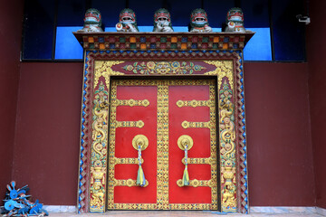 Ornate door handles and prayer scarves on ancient Buddha park monastery at Ravangla in South Sikkim, India. Red color door at Buddha Park of Ravangla. Door handles at Buddha Park Monastery in Sikkim.