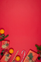 New Year and Christmas presents, handmade gift boxes wrapped with red paper and decorated fir tree branches, flat lay, red background. Copy space. Concepts of greeting card. Top view.