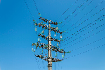 Power lines and a pole against the blue sky. High-voltage power transmission line.