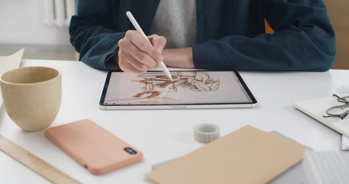 Crop view of illustrator hands drawing picture on tablet screen. Talanted graphic designer using digital pad and stylus while sitting and working on project. Indoors