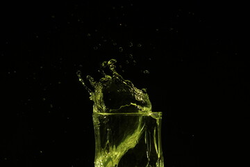 splash of water in a glass by ice cube on black background