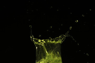 splash of water in a glass by ice cube on black background