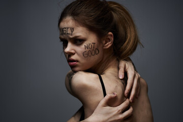 woman with offensive inscriptions on her body touching herself with hands stress frustration hate