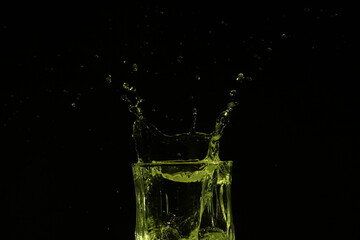 splash of water in a glass by ice cube on black background