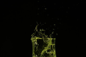 splash of water in a glass by ice cube on black background