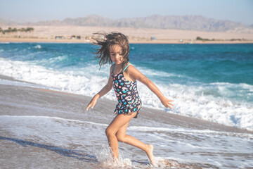 Portrait of a cheerful little girl in a bathing suit by the sea