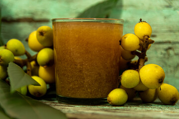Glass of loquat fruit juice (Eriobotrya japonica) on aged wooden background