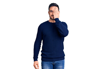 Young handsome man wearing casual clothes covering one eye with hand, confident smile on face and surprise emotion.