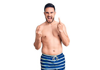 Young handsome man wearing swimwear showing middle finger doing fuck you bad expression, provocation and rude attitude. screaming excited