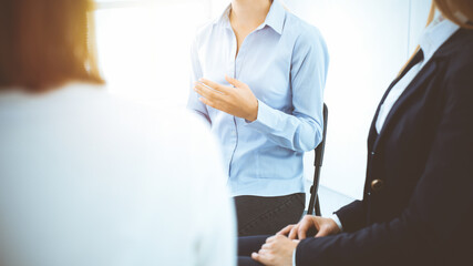 Group of people sitting in a circle during therapy in sunny office. Meeting of business team participating in training