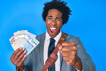 Handsome african american business man with afro hair holding canadian dollars annoyed and frustrated shouting with anger, yelling crazy with anger and hand raised