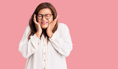Middle age latin woman wearing casual clothes and glasses covering ears with fingers with annoyed expression for the noise of loud music. deaf concept.